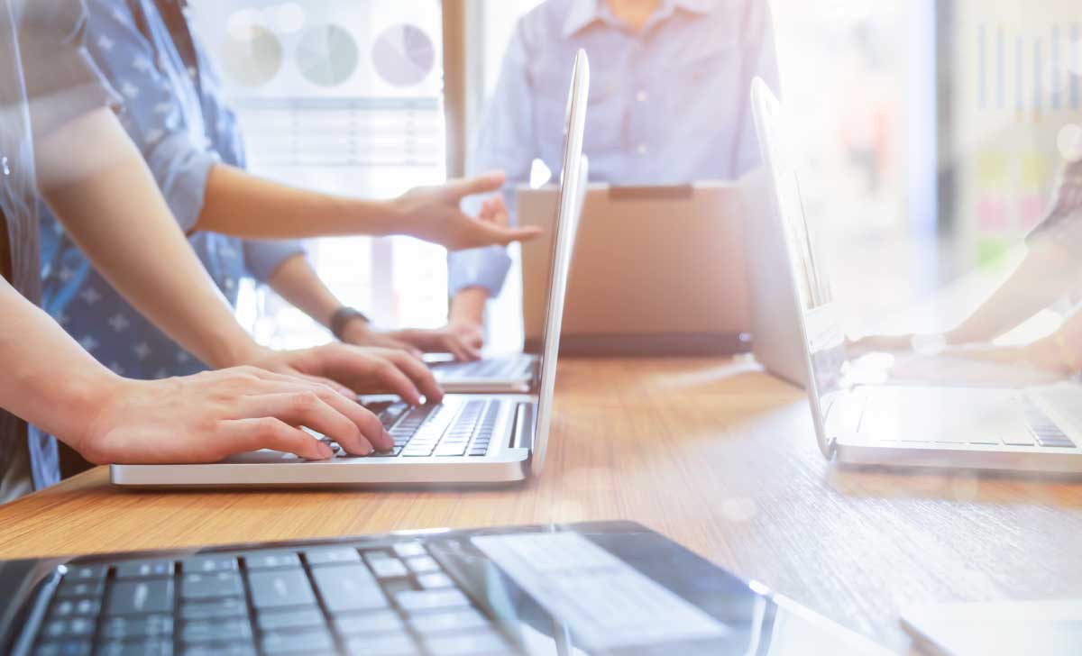 notebooks e calculadora sobre uma mesa e pessoas ao fundo