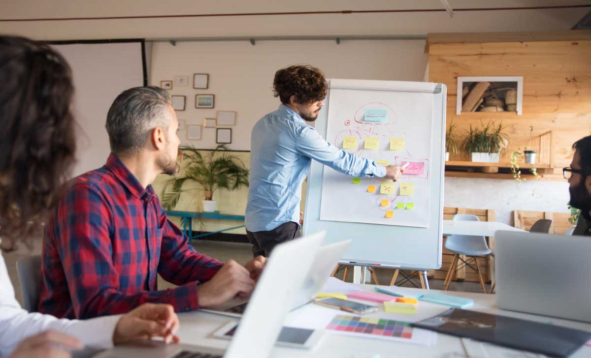 homem em pé apresentando a metodologia MASP em um quadro para outras pessoas