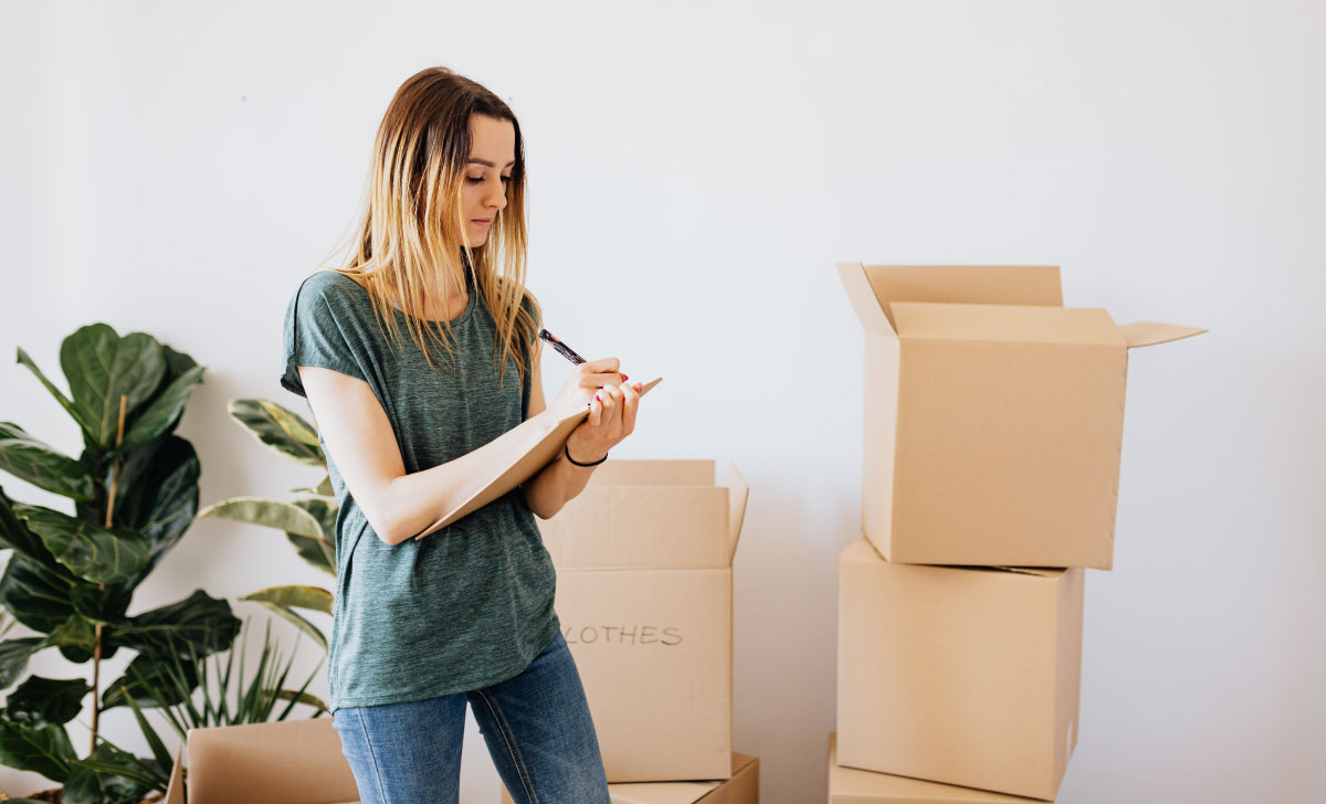 mulher utilizando folha de verificação ao redor de caixas