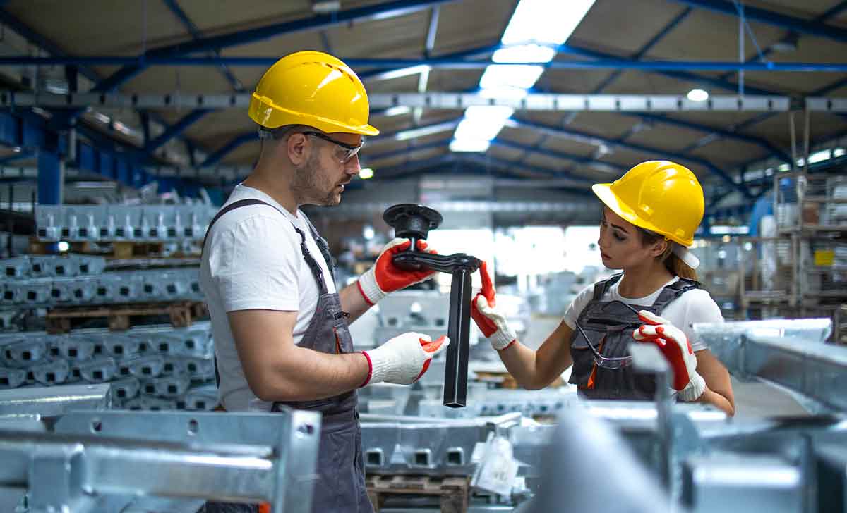 Profissionais conferindo uma peça e realizando a Gestão da Qualidade Total